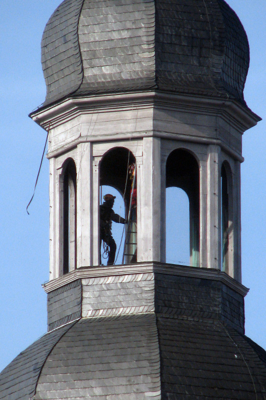 Zufallstreffer: In luftiger Höhe arbeiten hier zwei angeseilte Arbeiter auf dem höchsten Punkt des Kirchturms von Stift Haug.