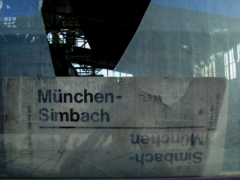 Zugschild München - Simbach hinter zerbrochener Scheibe.
